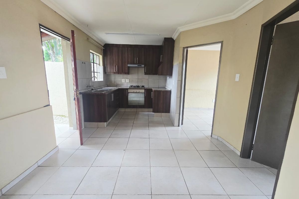A functional kitchen featuring dark wood cabinetry, built-in oven and hob, tiled flooring, and direct access to the exterior.