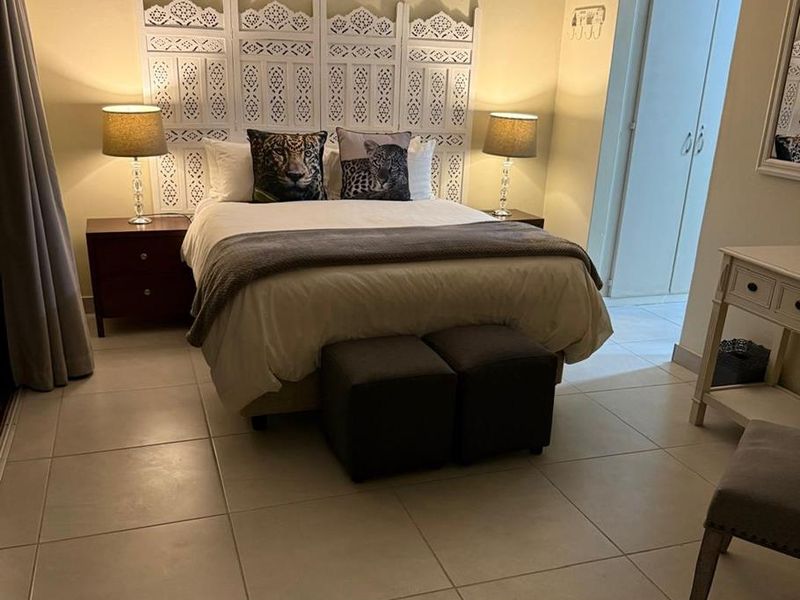 A well-maintained bedroom featuring neutral tiled flooring, cove ceiling detailing, and built-in cupboard storage.