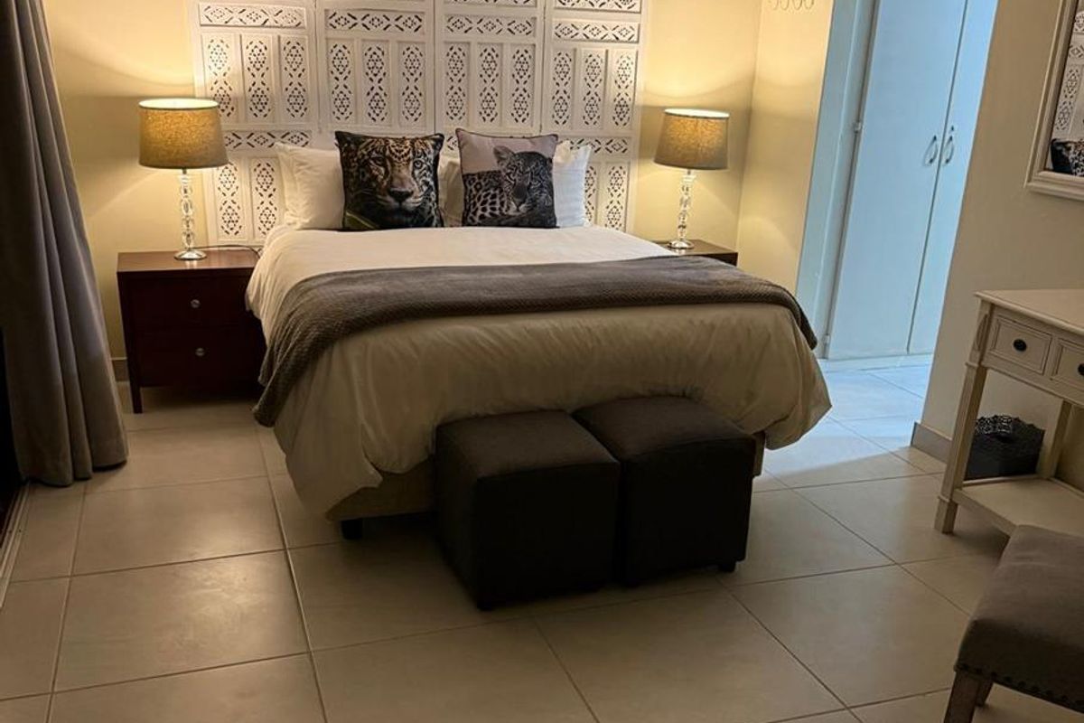 A well-maintained bedroom featuring neutral tiled flooring, cove ceiling detailing, and built-in cupboard storage.
