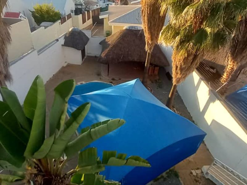 Aerial view of the rear garden featuring a swimming pool, a thatched lapa, and perimeter boundary walls.