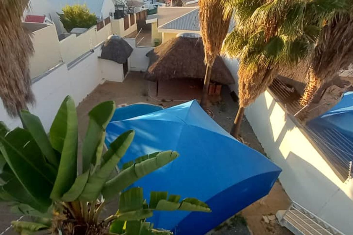 Aerial view of the rear garden featuring a swimming pool, a thatched lapa, and perimeter boundary walls.