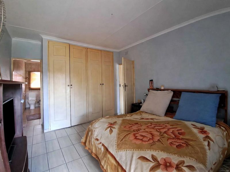 A bedroom featuring built-in cupboards, tiled flooring, and direct access to an en-suite bathroom.