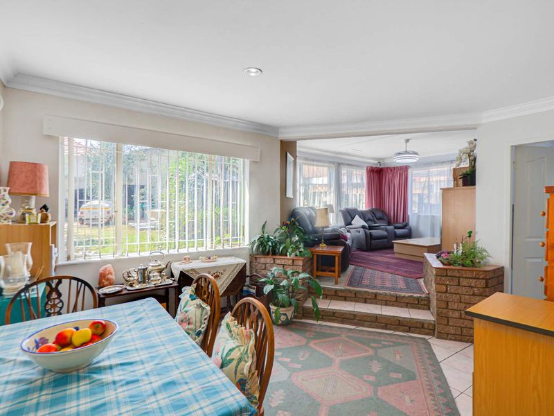 Open plan living and dining area featuring a sunken lounge, brick accents, tiled flooring, and large windows with security bars.
