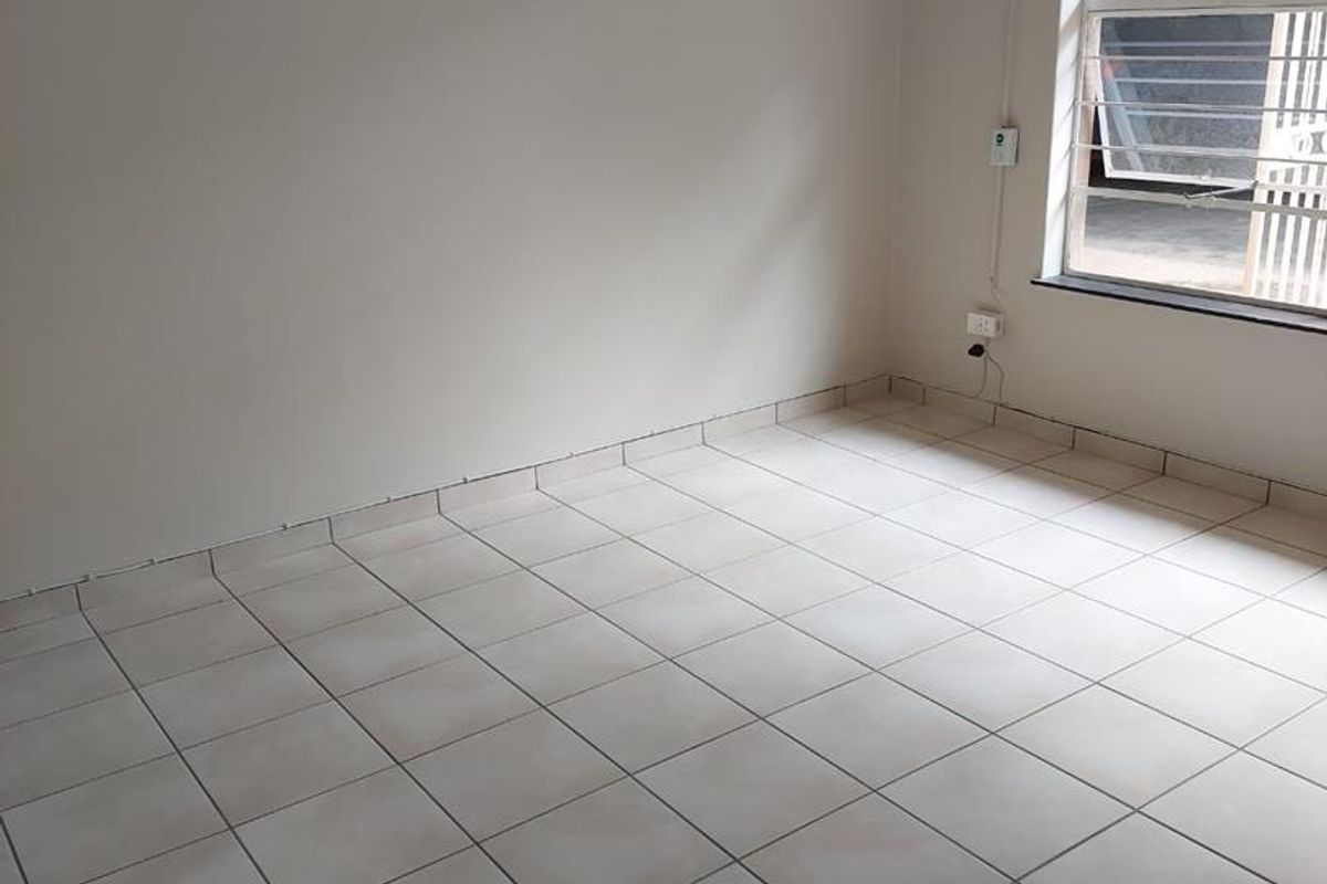 An empty bedroom featuring neutral tiled flooring and a functional louvre window, providing a blank canvas for personalization.