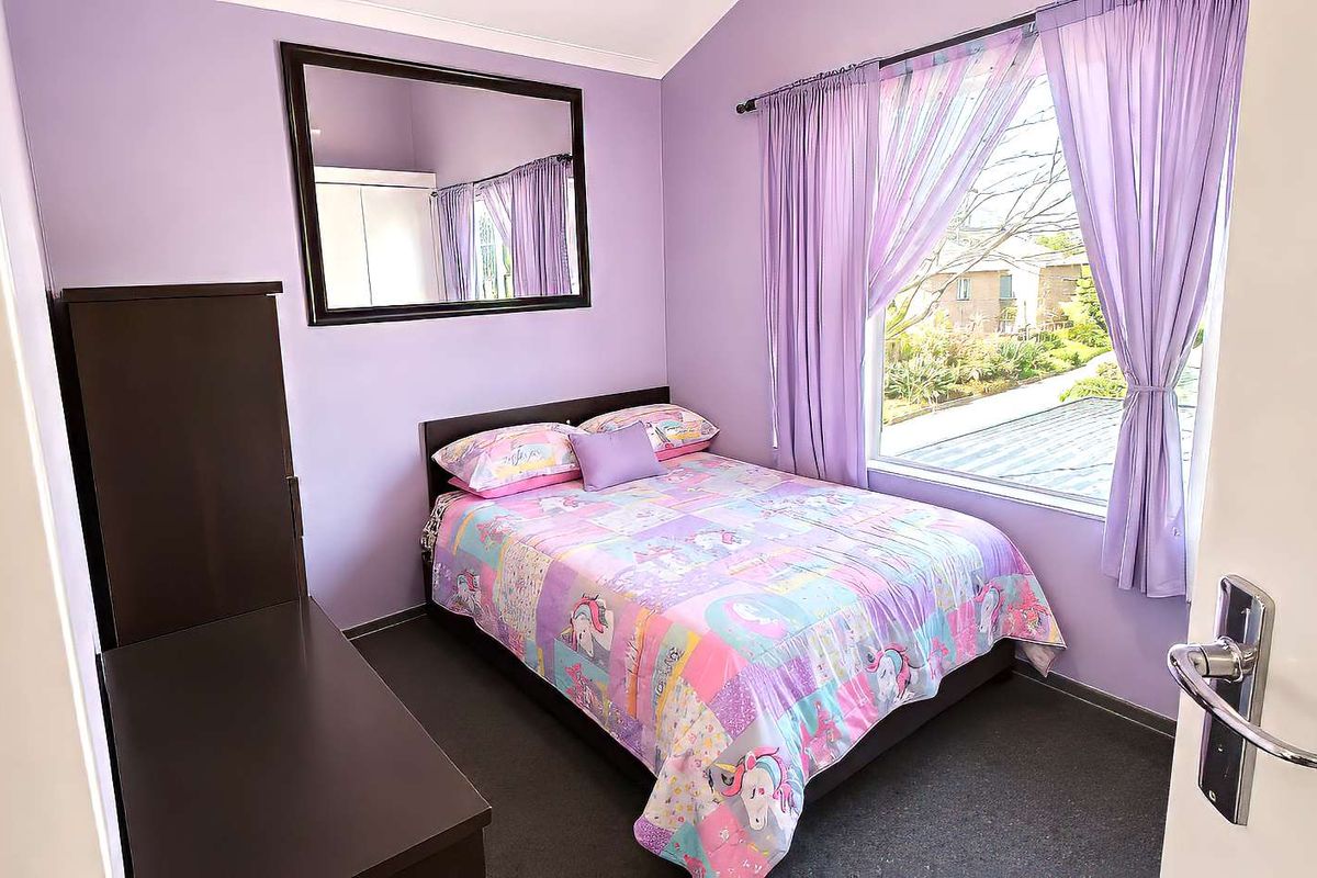 A bedroom featuring a large window with natural light, neutral carpeting, and built-in wardrobe storage.