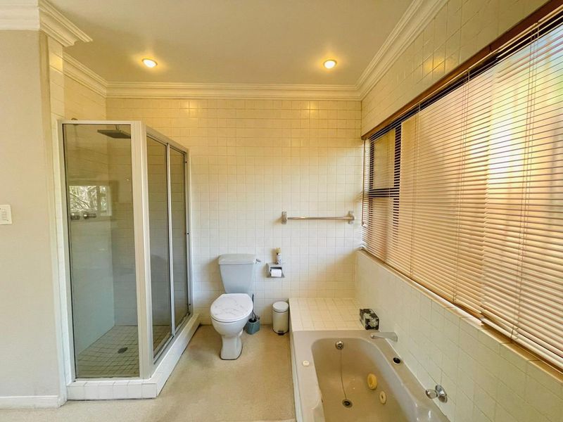 A functional bathroom featuring a glass-enclosed shower, a built-in bathtub, and tiled wall finishes with recessed lighting.