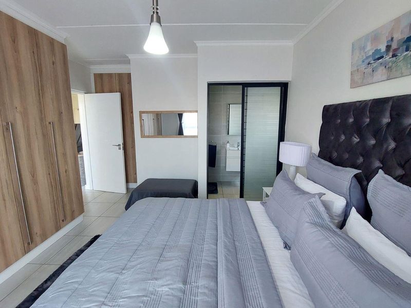 Spacious bedroom featuring built-in cupboards, tiled flooring, and an integrated en-suite bathroom with a sliding door entry.