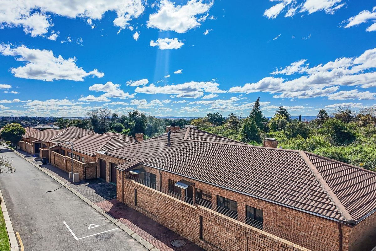 Aerial view of a cluster housing complex featuring face-brick facades, tiled roofs, and paved driveway access within a landscaped estate setting.