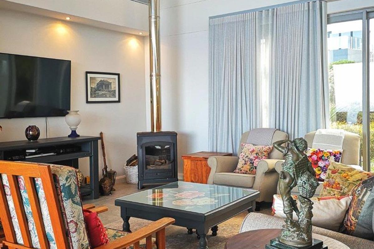 Spacious living room featuring a vaulted ceiling, clerestory windows, and a modern freestanding fireplace with a prominent flue pipe.