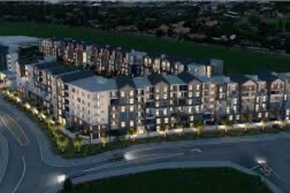An aerial view of a modern multi-story apartment complex development, showcasing the building architecture and surrounding street layout.