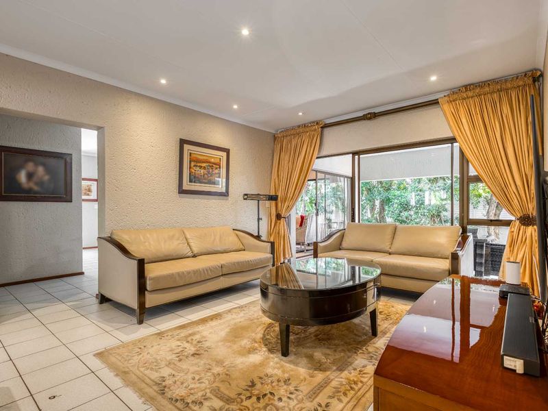 A comfortable living room featuring tiled flooring, textured walls, recessed lighting, and large sliding glass doors providing access to the outdoor patio area.