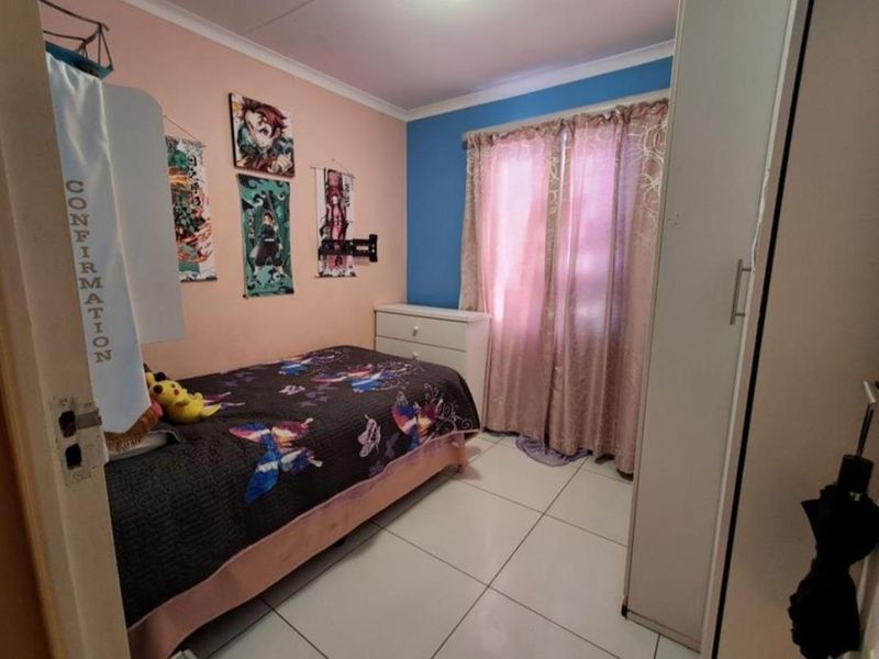 A bedroom featuring tiled flooring, a built-in wardrobe, and cove cornice detailing, currently styled with personal decor.