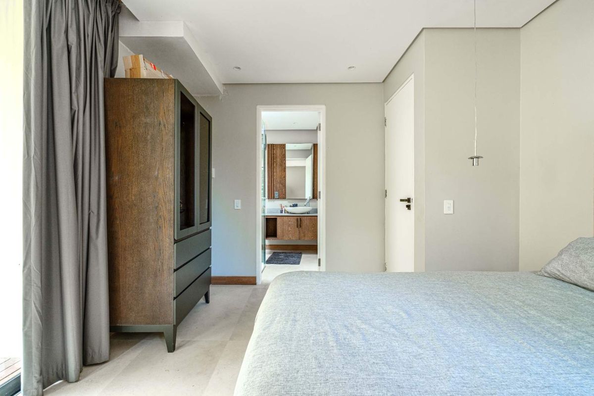 A well-maintained bedroom featuring neutral tones, recessed lighting, and direct access to an en-suite bathroom with a modern vanity.