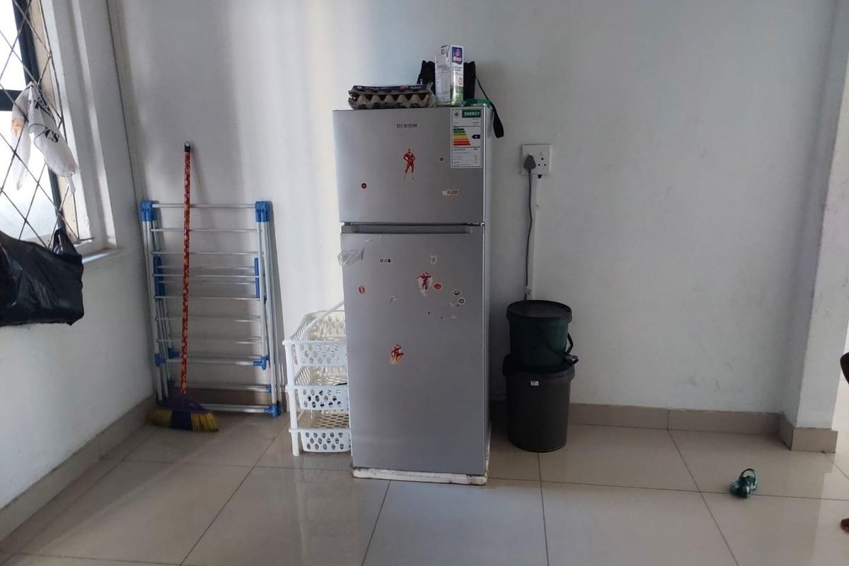 A functional kitchen area featuring tiled flooring and a dedicated electrical outlet, providing a practical space for food storage and preparation.