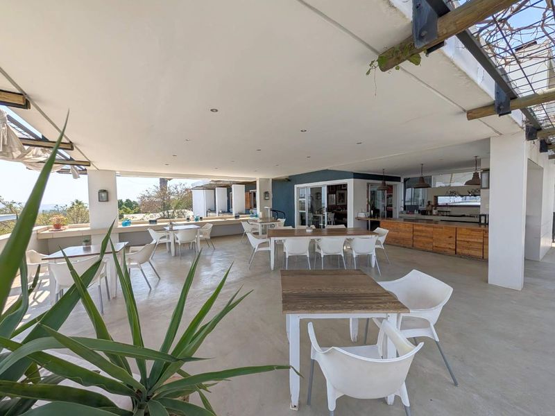 Spacious covered outdoor patio featuring a built-in bar counter, concrete flooring, and recessed lighting, ideal for guest house entertainment and dining.