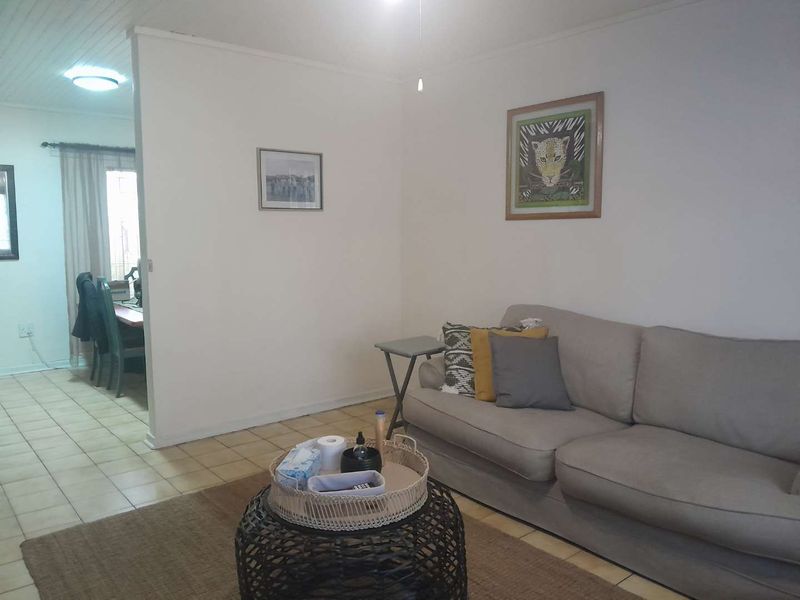 A living room area featuring tiled flooring and a tongue and groove ceiling, with an open transition to an adjacent dining space.