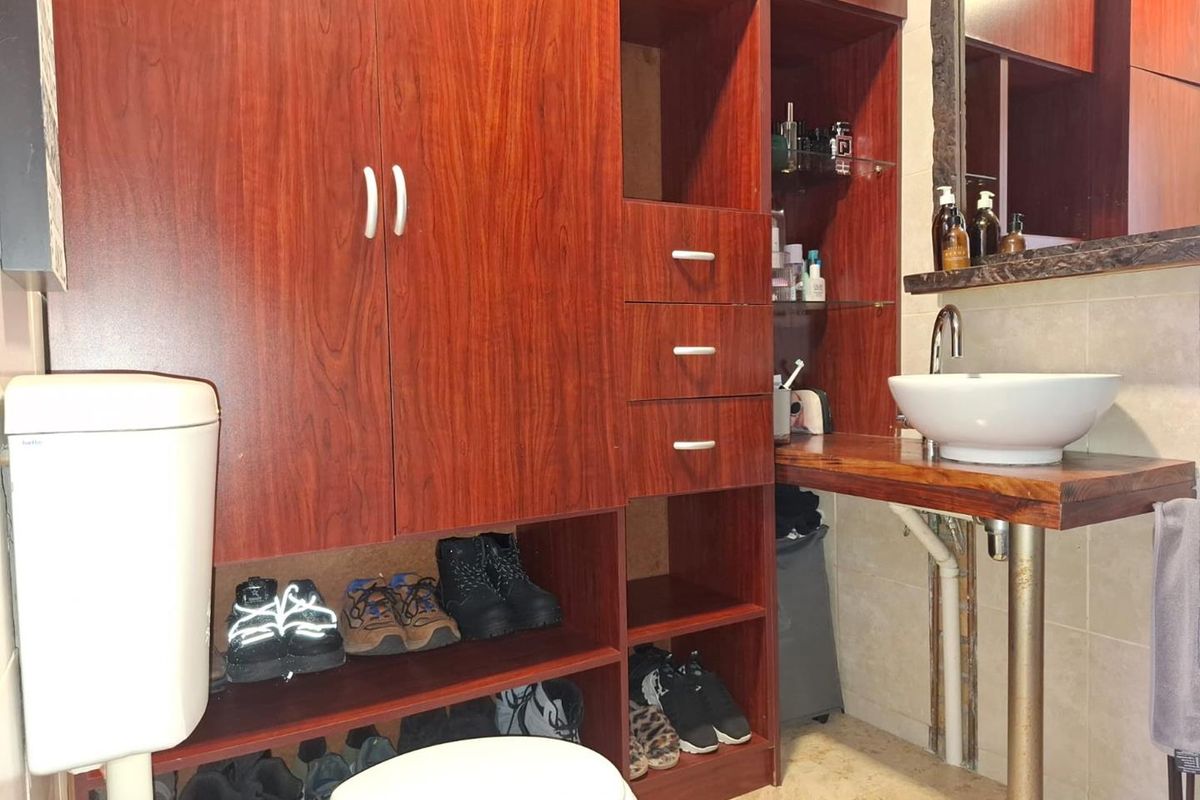 Bathroom featuring built-in wooden cabinetry, a vessel sink with chrome faucet, and tiled flooring.
