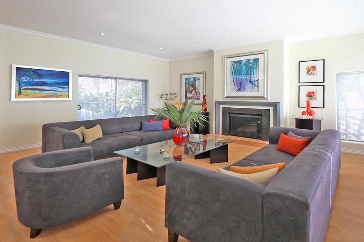 Spacious living room featuring a built-in fireplace with a stone surround, recessed lighting, and light-toned wood flooring.