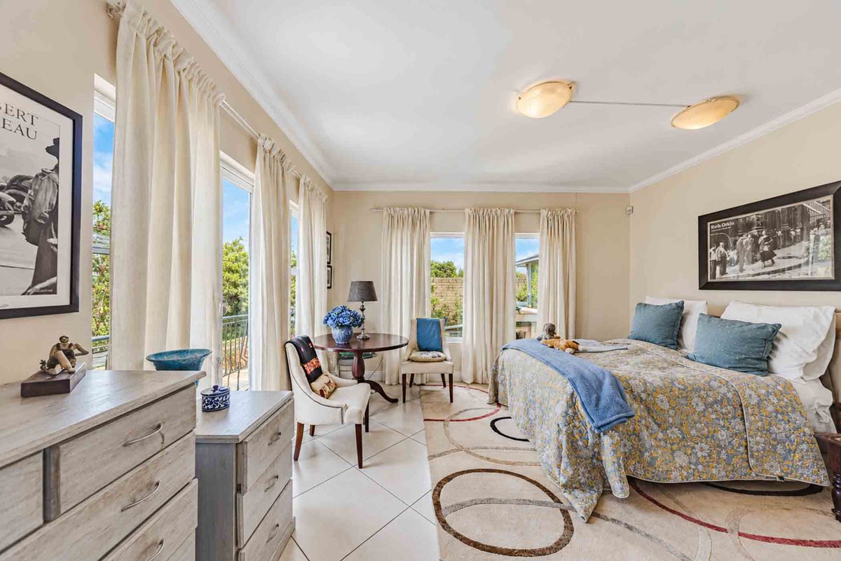 A bright and spacious bedroom featuring tiled flooring, neutral walls, and large sliding glass doors that provide access to an outdoor area.