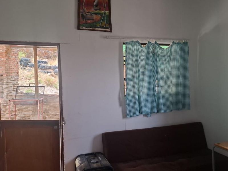 A simple bedroom featuring a timber door leading to an outdoor area and a window with security bars.