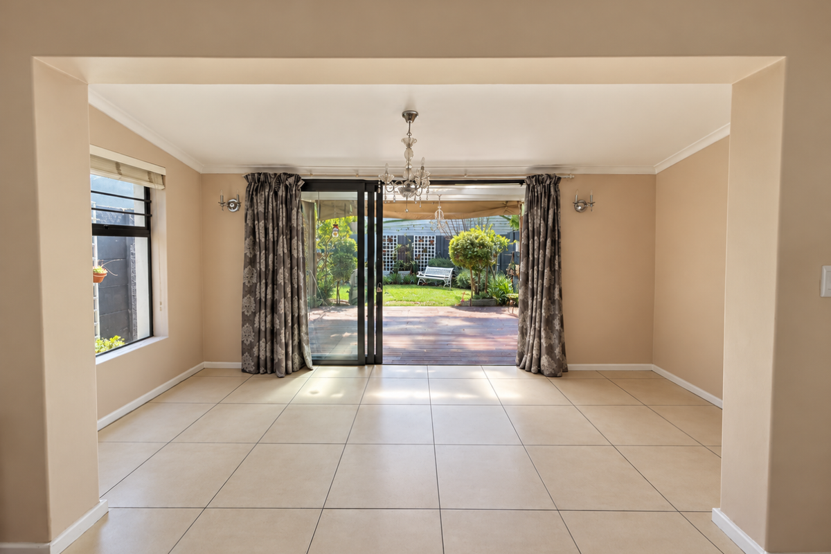 Spacious, light-filled living area featuring neutral tiled flooring and large sliding glass doors that open directly onto a rear patio and garden.