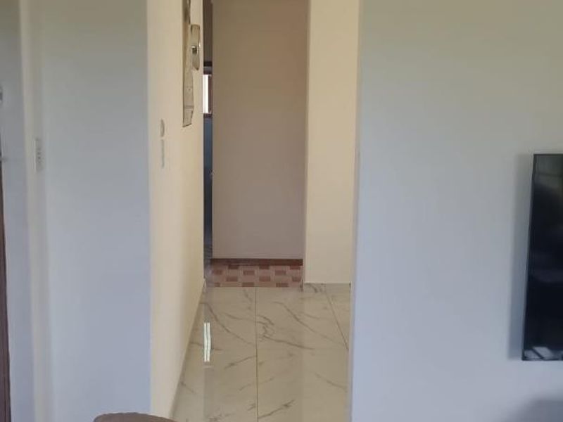 A view of a hallway featuring marble-look floor tiles and coving, connecting to other areas of the home.