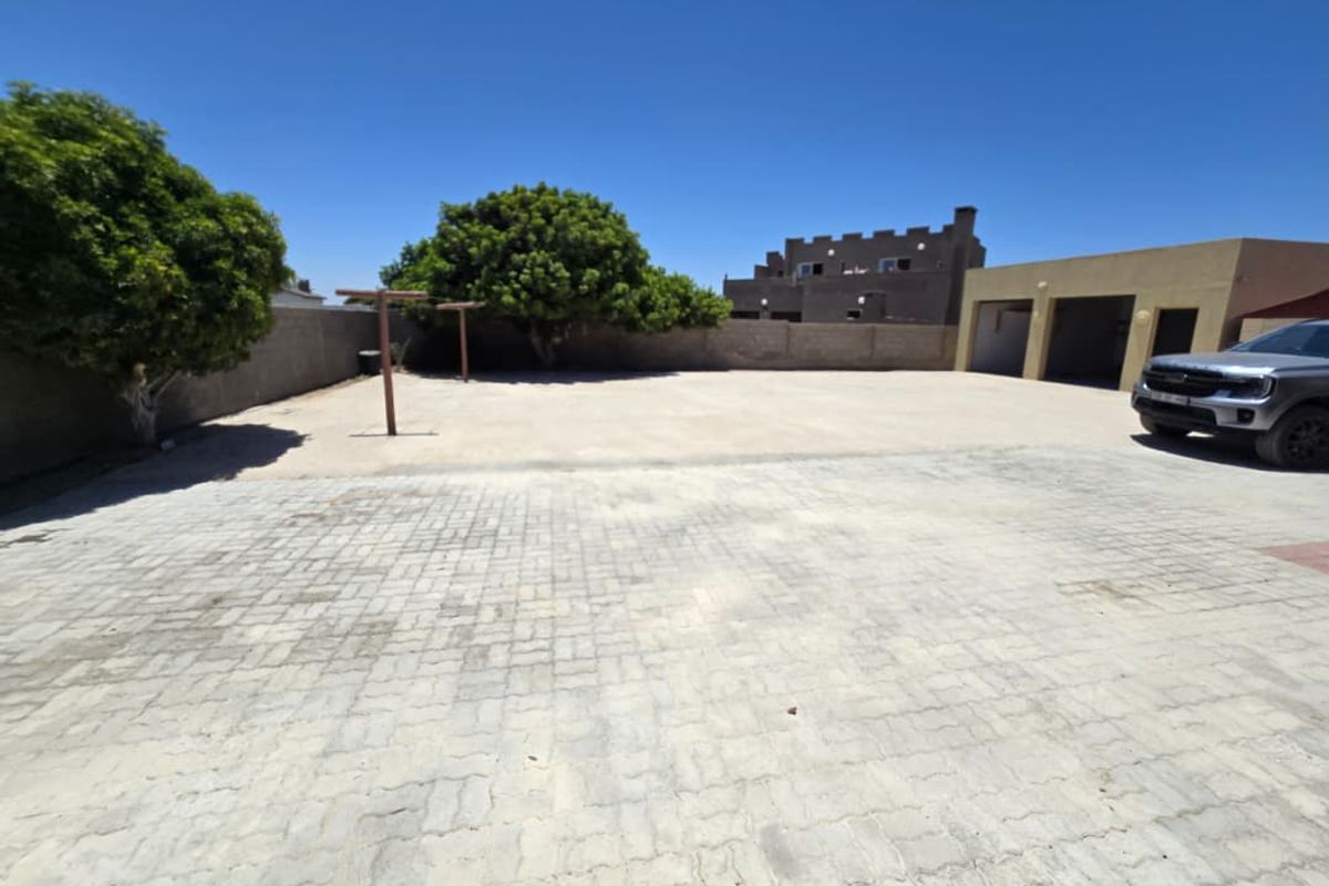 Spacious paved rear courtyard area featuring a multi-car garage and perimeter boundary walls, offering ample outdoor space.