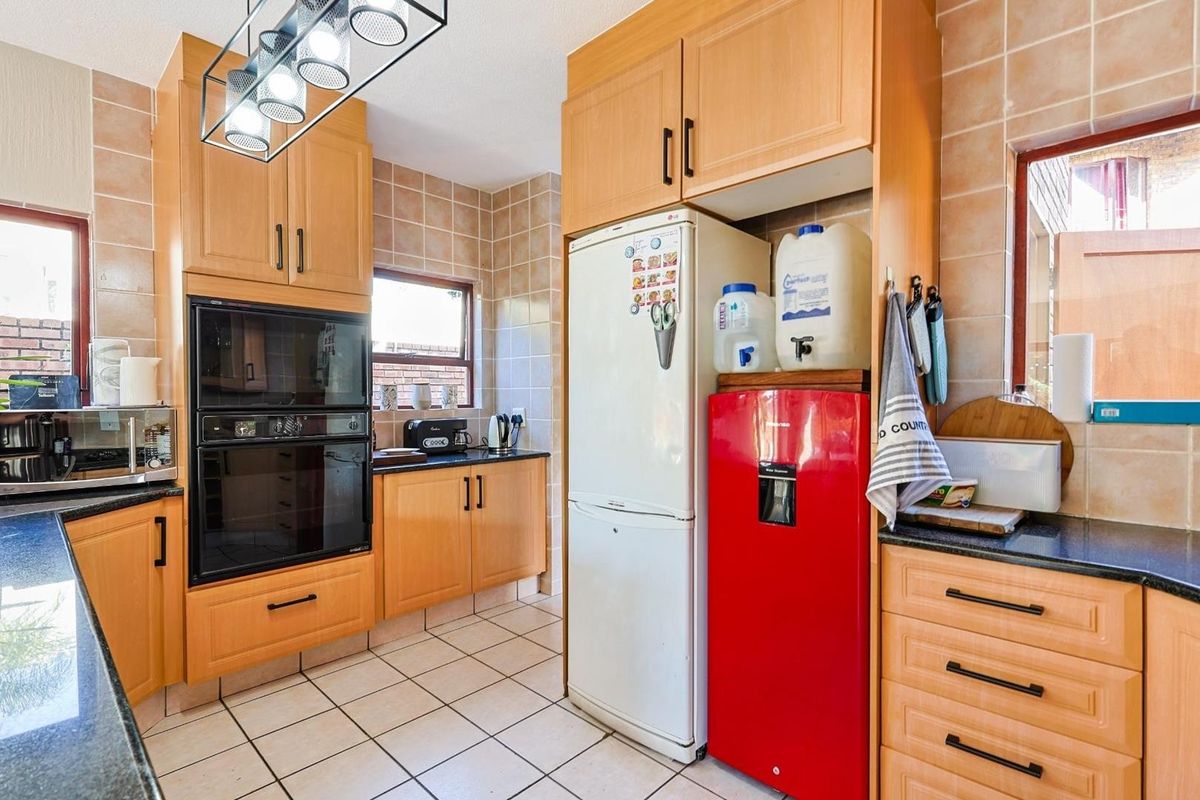 A functional kitchen featuring light wood cabinetry, granite countertops, tiled splashbacks, and a built-in oven, offering a practical layout for daily meal preparation.
