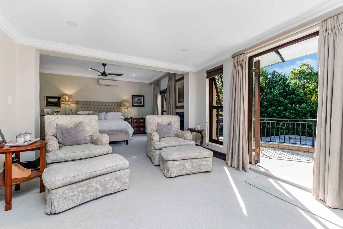Spacious bedroom suite featuring plush carpeting, a ceiling fan, and direct access to a private balcony through glass doors.