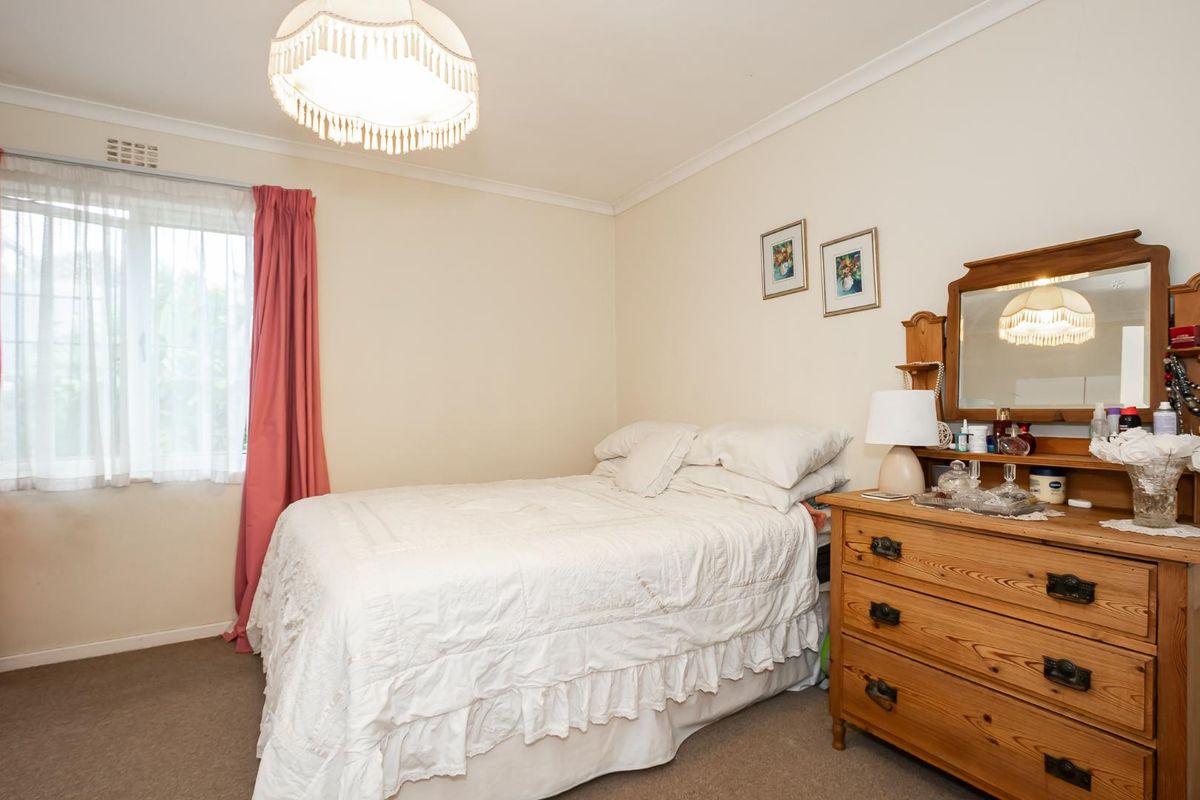 A standard bedroom featuring neutral walls, carpeted flooring, and a window with curtains, providing a functional and comfortable living space.