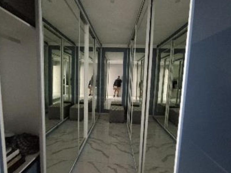 A modern walk-in dressing area featuring floor-to-ceiling mirrored built-in wardrobes and polished marble-look tiled flooring.