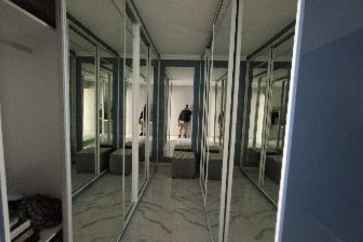 A modern walk-in dressing area featuring floor-to-ceiling mirrored built-in wardrobes and polished marble-look tiled flooring.