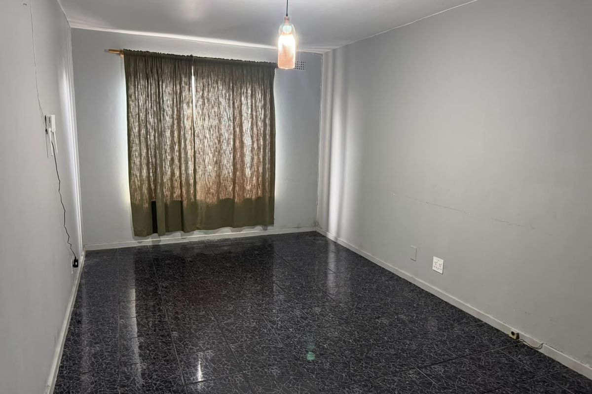 An empty living room featuring dark tiled flooring and neutral walls, providing a blank canvas for interior design and personalization.