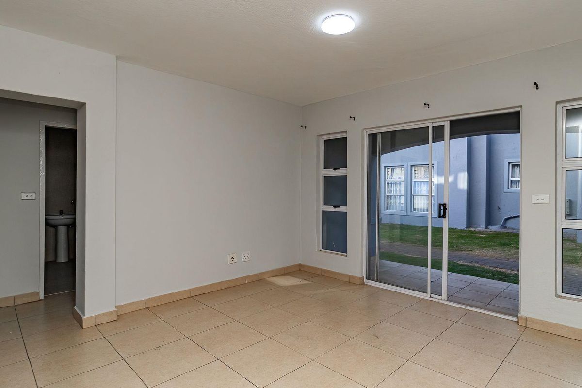 An empty, tiled living area featuring a sliding glass door that provides access to an outdoor patio space.