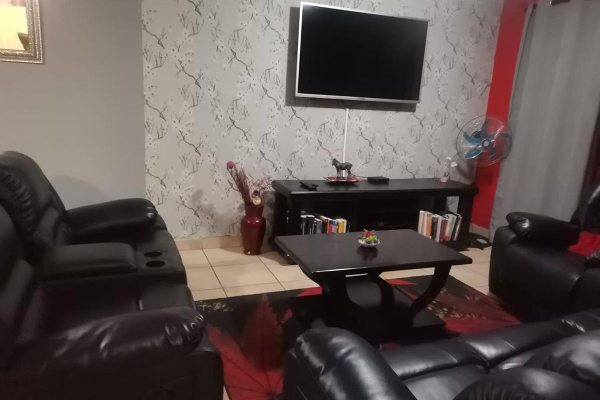A living room featuring tiled flooring and a decorative feature wall, providing a functional space for relaxation and entertainment.