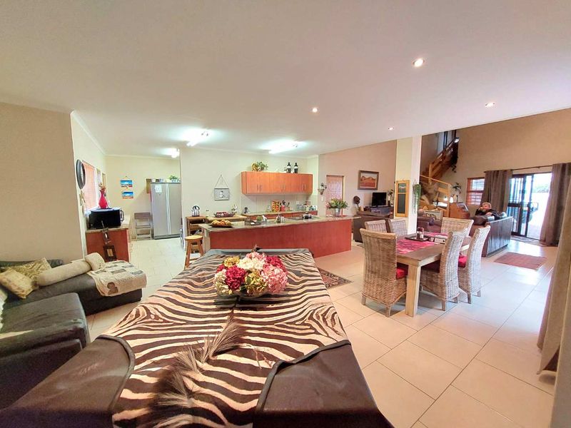 Spacious open-plan living area featuring a kitchen with a central island, dining space, and tiled flooring throughout.