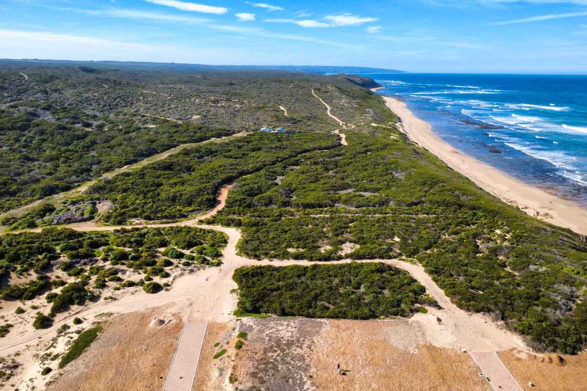 Aerial view of vacant residential land situated along the coastline, featuring natural vegetation and dirt access roads.