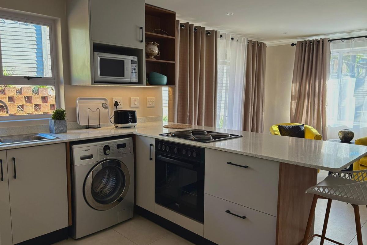 Modern kitchen featuring sleek cabinetry, stone countertops, integrated oven, electric hob, and built-in microwave, offering a functional and contemporary cooking space.