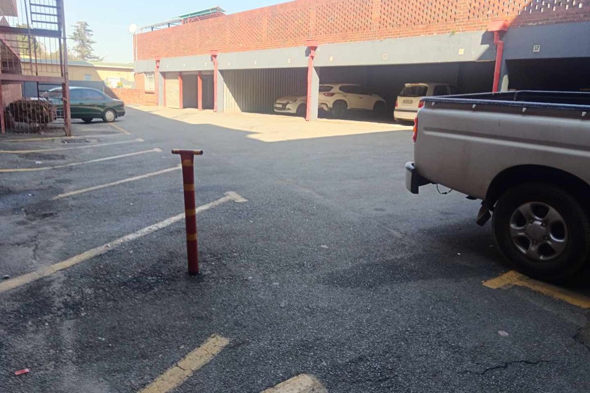 An outdoor parking area featuring multiple covered parking bays with a brick facade and asphalt driveway.