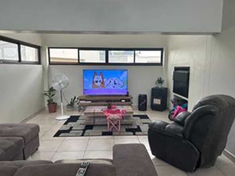 A living room featuring tiled flooring, built-in shelving, and horizontal windows, providing a functional space for relaxation.