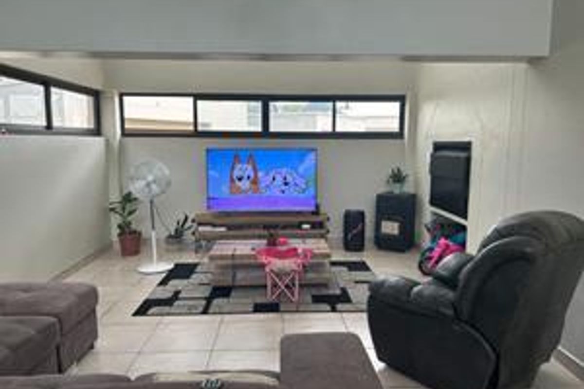 A living room featuring tiled flooring, built-in shelving, and horizontal windows, providing a functional space for relaxation.