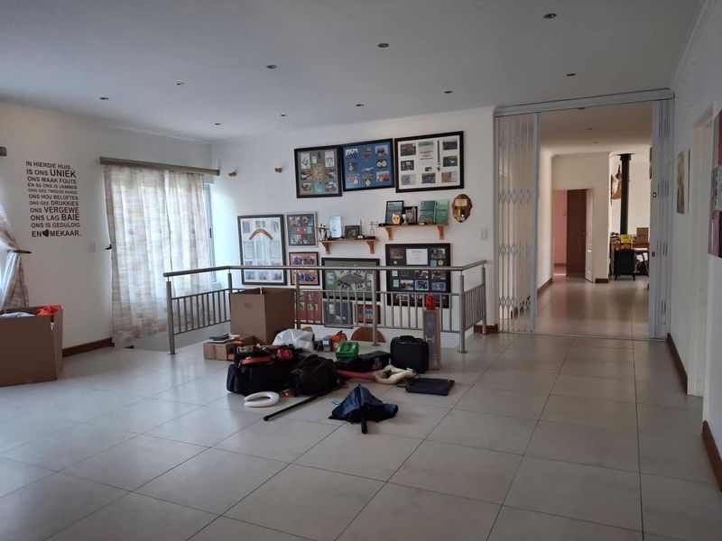 Spacious living area featuring neutral tiled flooring, recessed lighting, and a modern stainless steel balustrade overlooking a lower level.