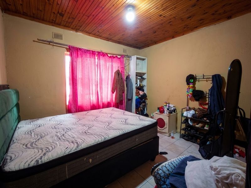 A bedroom featuring a timber-clad ceiling and tiled flooring, offering a functional space with potential for cosmetic updates to enhance its overall appeal.