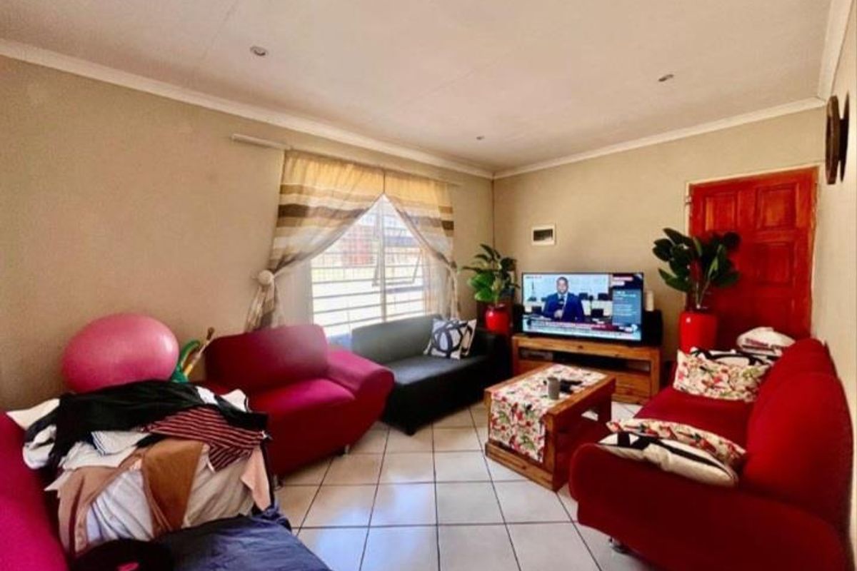 A comfortable living room featuring tiled flooring, recessed ceiling lighting, and a large window allowing natural light into the space.