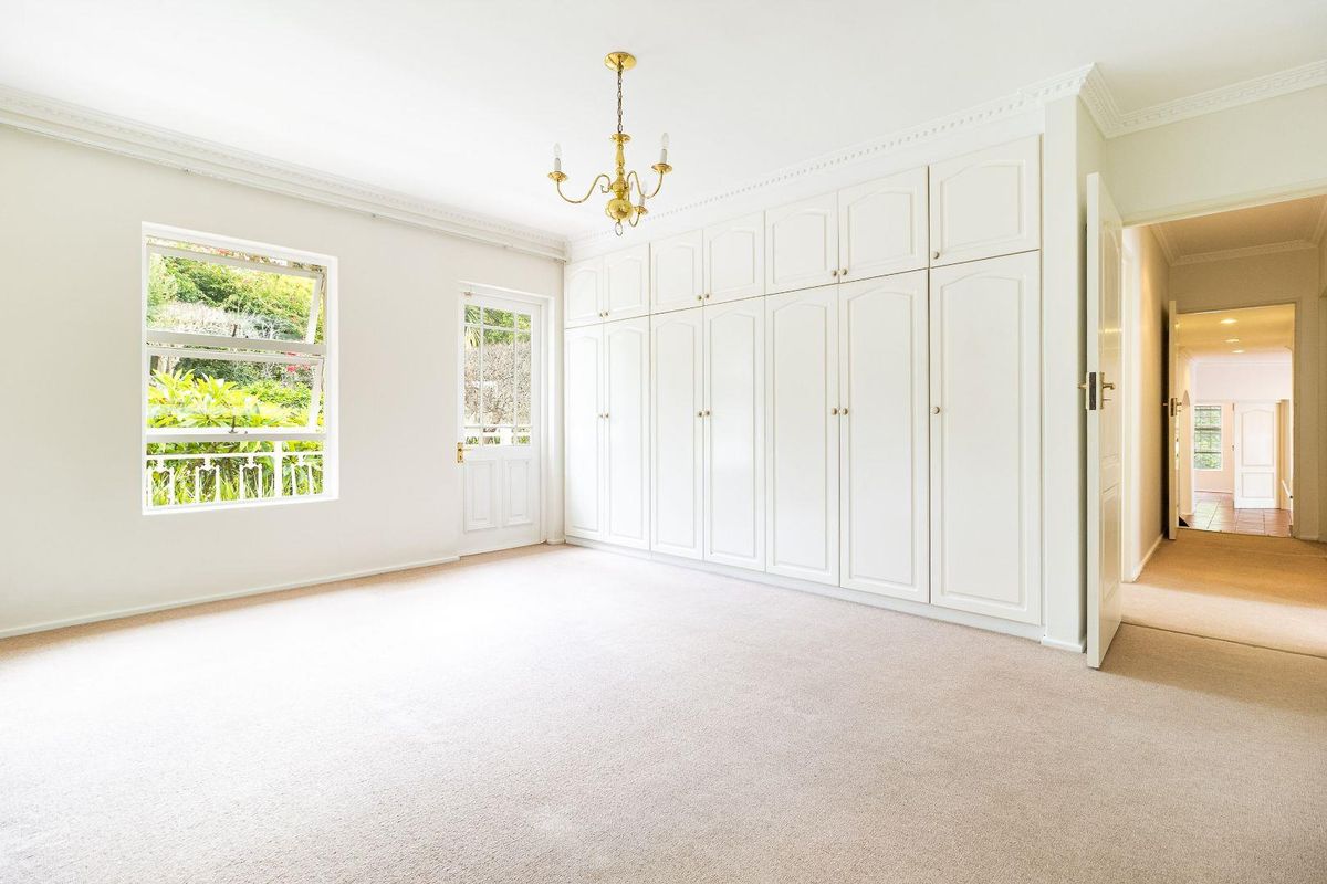 Spacious bedroom featuring extensive built-in cabinetry, neutral carpeting, crown molding, and direct access to an outdoor area through a glass-paneled door.