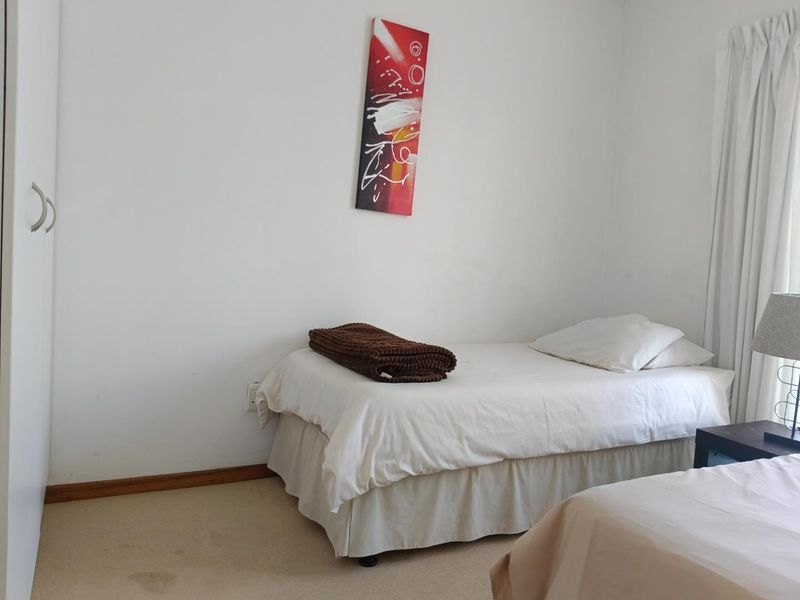 A functional bedroom featuring neutral walls, carpeted flooring, and a built-in wardrobe, offering a simple and practical living space.