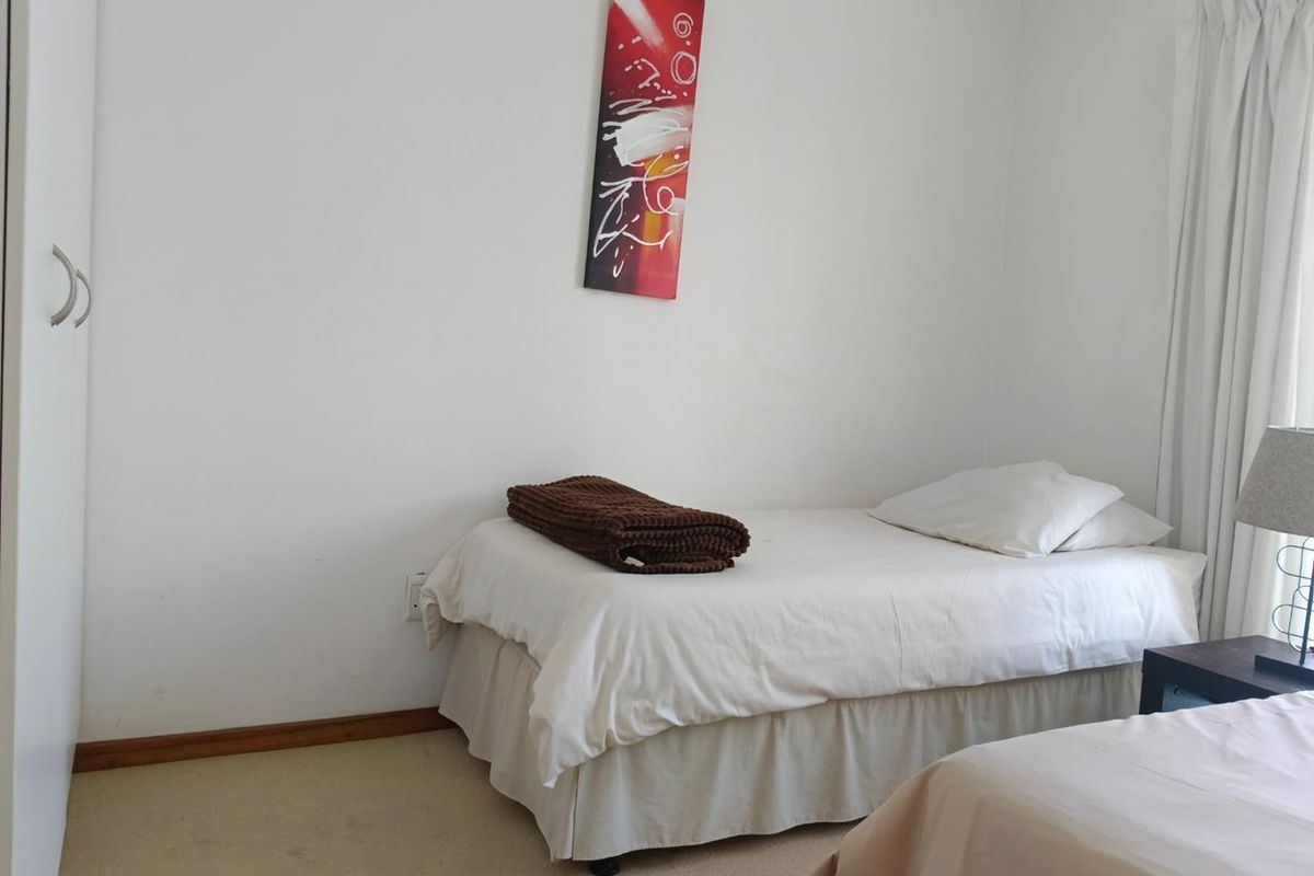 A functional bedroom featuring neutral walls, carpeted flooring, and a built-in wardrobe, offering a simple and practical living space.