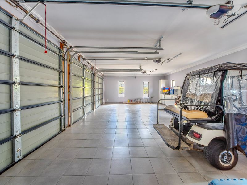 Spacious triple garage featuring tiled flooring, automatic door mechanisms, and built-in storage cabinetry, providing ample space for vehicles and additional utility storage.