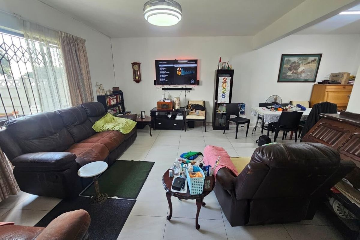 A spacious living area featuring neutral tiled flooring and a ceiling light fixture, providing a functional base for comfortable family living.