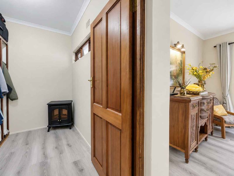 A bright hallway featuring modern laminate flooring, a built-in wardrobe, and a solid timber door leading to an adjacent living space.